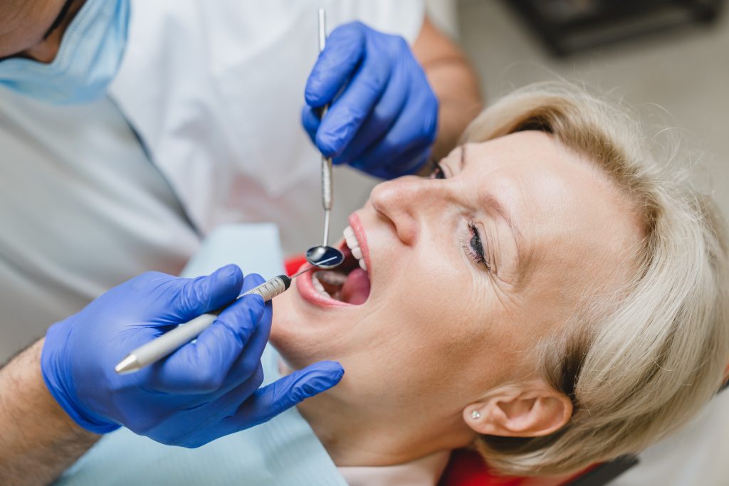 doctor examining a woman's decayed tooth, root canal therapy